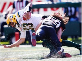 Edmonton Eskimos quarterback Mike Reilly is tackled by Alex Singleton of the Calgary Stampeders during CFL football on Monday, September 4, 2017.