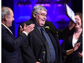 Sports Columnist Terry Jones holds up his award after being inducted into the Sports Hall of Fame during the Salute to Excellence Hall of Fame Induction Ceremony at the Winspear Centre in Edmonton June 11, 2018.