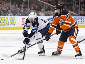 The Edmonton Oilers' Cooper Marody (65) battles the Winnipeg Jets' Andrew Copp (9) and Joe Morrow (70) during first period pre-season NHL action at Rogers Place, Thursday Sept. 20, 2018.