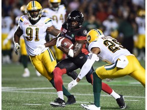 Ottawa Redblacks' Quincy McDuffie runs between Edmonton Eskimos defensive end Marcus Howard (91) and Eskimos defensive back Mercy Maston (29) during first half CFL football action in Ottawa on Aug. 10, 2017.