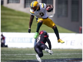 Edmonton Eskimos' C.J. Gable, top, leaps over a tackle from Calgary Stampeders' Ciante Evans during first half CFL football action in Calgary, Monday, Sept. 3, 2018.