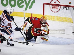 Edmonton Oilers' Kailer Yamamoto, centre, scores on Calgary Flames' goalie David Rittich, from the Czech Republic, during first period preseason NHL hockey action in Calgary, Monday, Sept. 17, 2018.
