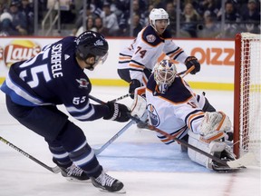 Winnipeg Jets' Mark Scheifele (55) scores on Edmonton Oilers' goaltender Mikko Koskinen (19) during second period preseason NHL hockey action in Winnipeg, Sunday, Sept. 23, 2018.