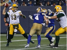 Edmonton Eskimos QB Mike Reilly throws under pressure from Winnipeg Blue Bombers LB Adam Bighill (4) and DE Tristan Okpalaugo during CFL action in Winnipeg on Thurs., June 14, 2018.