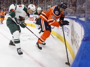 Minnesota Wild centre Joel Eriksson Ek (14) and Edmonton Oilers centre Kyle Brodziak (28) battle in the corner during second period NHL action at Rogers Place on Tuesday October 30, 2018.
