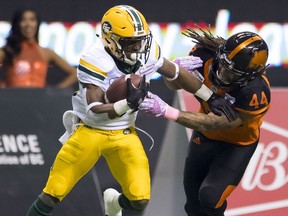 Edmonton Eskimos defensive tackle Almondo Sewell (90) fights for control of the ball with BC Lions defensive back Isaiah Guzylak-Messam (44) during CFL football action in Vancouver, B.C., on Friday, Oct. 19, 2018.
