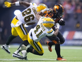 Edmonton Eskimos defensive back Chris Edwards (26) and Edmonton Eskimos defensive back Monshadrik Hunter (41) try to take down BC Lions running back Tyrell Sutton (13) during CFL football action in Vancouver, B.C., on Friday, Oct. 19, 2018.