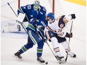 Vancouver Canucks defenseman Ashton Sautner (59) fights for control of the puck with Edmonton Oilers center Kyle Brodziak (28) as Vancouver Canucks goaltender Anders Nilsson (31) look on during first period NHL pre-season action at Rogers Arena in Vancouver, Tuesday, Sept, 18, 2018.