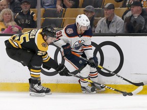 Boston Bruins defenseman Brandon Carlo (25) and Edmonton Oilers left wing Drake Caggiula (91) battle for the puck along the boards during the first period of an NHL hockey game Thursday, Oct. 11, 2018, in Boston. Mary Schwalm / AP