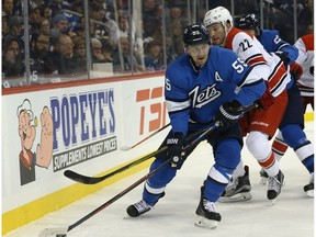 Winnipeg Jets centre Mark Scheifele (left) slips the check of Carolina Hurricanes defenceman Brett Pesce in Winnipeg on Sun., Oct. 14, 2018.