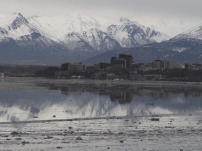 In this Feb. 12, 2016, file photo, the Chugach Mountains and the buildings of downtown Anchorage, Alaska, are reflected in the still waters of Cook Inlet.