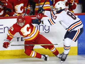 Edmonton Oilers' Matthew Benning, right, checks Calgary Flames' Johnny Gaudreau during second period NHL hockey action in Calgary, Saturday, Nov. 17, 2018.