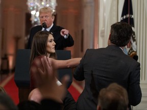 U.S. President Donald Trump looks on as a White House aide tries to take away a microphone from CNN reporter Jim Acosta during a news conference at the White House in Washington, Wednesday, Nov. 7, 2018.