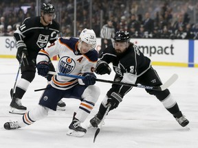 Edmonton Oilers center Ryan Nugent-Hopkins, center, shoots a backhander with Los Angeles Kings defenseman Drew Doughty, right, defending and center Anze Kopitar, left, of Slovenia, trailing during the first period of an NHL hockey game in Los Angeles, Sunday, Nov. 25, 2018.