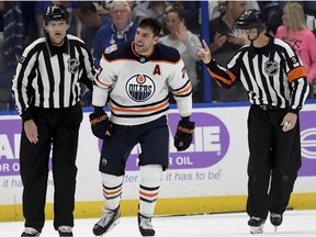 Linesman Tim Nowak (77) skates Edmonton Oilers left wing Milan Lucic (27) toward the penalty box during the third period of the team's NHL hockey game against the Tampa Bay Lightning on Tuesday, Nov. 6, 2018, in Tampa, Fla.