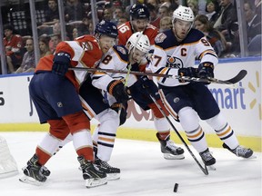 Florida Panthers defenseman Mike Matheson (19), Edmonton Oilers right wing Ty Rattie (8) and center Connor McDavid, right, go for the puck during the first period of an NHL hockey game, Thursday, Nov. 8, 2018, in Sunrise, Fla.