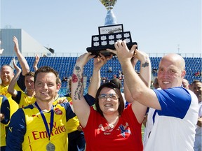 (left to right) Matthew Harris, Cst. Daniel Woodall's widow Claire Woodall, and Bruce McGregor hold up the Woodall Cup at Clarke Stadium, in Edmonton Alta. on Sunday July 26, 2015. The charity soccer game pitted a team of British ex-pats against Edmonton Police Service officers. The game ended in a 2-2 tie.