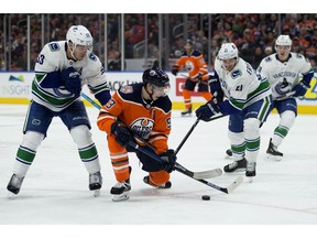 The Edmonton Oilers' Ryan Nugent-Hopkins (93) battles the Vancouver Canucks' Bo Horvat (53) and Loui Eriksson (21) during second period NHL action at Rogers Place, in Edmonton on Thursday, Dec. 27, 2018.