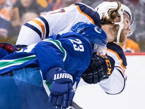 Edmonton Oilers' Connor McDavid, back, tries to fight off Vancouver Canucks' Alexander Edler, of Sweden, as they skate after the puck during first period NHL hockey action in Vancouver on Sunday, Dec. 16, 2018. THE CANADIAN PRESS/Darryl Dyck ORG XMIT: VCRD104