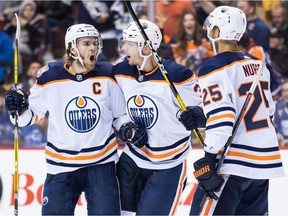 Edmonton Oilers' Connor McDavid, from left to right, Alex Chiasson and Darnell Nurse celebrate Chiasson's goal during third period NHL hockey action against the Vancouver Canucks, in Vancouver on Sunday, Dec. 16, 2018.