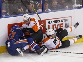 Edmonton centre Connor McDavid (97) crashes into the boards with Philadelphia defenceman Brandon Manning (23) and defenceman Michael Del Zotto (15) during the second period of a NHL game between the Edmonton Oilers and the Philadelphia Flyers at Rexall Place in Edmonton, Alta. on Tuesday November 3, 2015.