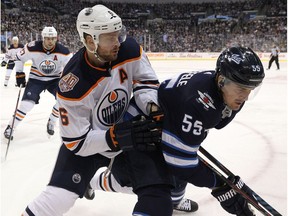 Edmonton Oilers defenceman Adam Larsson (left) checks Winnipeg Jets centre Mark Scheifele in Winnipeg on Thurs., Dec. 13, 2018. Kevin King/Winnipeg Sun/Postmedia Network