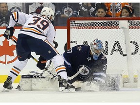 Edmonton Oilers forward Alex Chiasson tips the puck past Winnipeg Jets goaltender Connor Hellebuyck in Winnipeg on Thurs., Dec. 13, 2018.