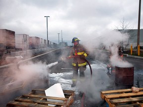 A fireman works to extinguish a burning barrel at Canada Posts' Gateway Postal Facility, after union groups and activists blocked truck traffic to and from the facility in support of Canada Post workers who were recently legislated back to work by the federal government, in Mississauga, Ont., Saturday, Dec. 1, 2018.