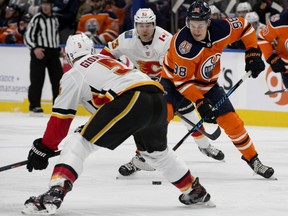 The Edmonton Oilers' Jesse Puljujarvi (98) battles the Calgary Flames Mark Giordano (5) during first period NHL action at Rogers Place, in Edmonton Saturday Jan. 19, 2019.