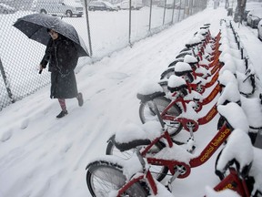 A woman walks past bike shares during a winter storm Jan. 13 in Washington, DC. This will likely be a common sight in Edmonton winters after bike share companies are established in the city.