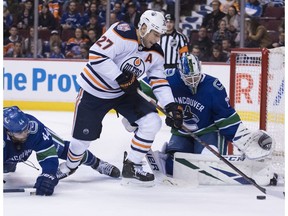 Vancouver Canucks defenceman Erik Gudbranson (44) tries to stop Edmonton Oilers left wing Milan Lucic (27) from getting a shot on Vancouver Canucks goaltender Jacob Markstrom (25) during first period NHL action at Rogers Arena in Vancouver, Wednesday, Jan. 16, 2019.