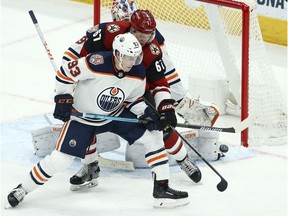 Edmonton Oilers center Ryan Nugent-Hopkins (93) and Arizona Coyotes left wing Lawson Crouse (67) try to get a stick on the puck during the third period of an NHL hockey game Wednesday, Jan. 2, 2019, in Glendale, Ariz. The Oilers defeated the Coyotes 3-1.