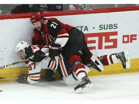 Arizona Coyotes center Derek Stepan (21) sends Edmonton Oilers center Connor McDavid (97) into the boards during the third period of an NHL hockey game Wednesday, Jan. 2, 2019, in Glendale, Ariz. The Oilers defeated the Coyotes 3-1.