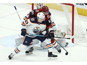 Edmonton Oilers center Ryan Nugent-Hopkins (93) and Arizona Coyotes left wing Lawson Crouse (67) try to get a stick on the puck during the third period of an NHL hockey game Wednesday, Jan. 2, 2019, in Glendale, Ariz. The Oilers defeated the Coyotes 3-1.