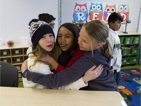Laia Maglisceau, left, Sofia Restauro ,middle and Kaitlyn Jesse, right, hug after inspecting there new grade five classroom after packing up from the old Mill Creek School and moving over to their brand new school building on Wednesday, Jan. 23, 2019, in Edmonton.