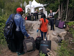 A Royal Canadian Mounted Police officer informs a migrant couple of the location of a legal border station, shortly before they illegally crossed from Champlain, N.Y., to Saint-Bernard-de-Lacolle, Que., using Roxham Rd. on Aug. 7, 2017.
