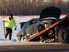 An Edmonton Police Service officer helps cleanup as a Toyota Corolla involved in a fatal single vehicle crash off the eastbound lanes of Anthony Henday Drive is towed west of the Manning Drive off ramp in Edmonton on Thursday, Feb. 21, 2019. Photo by Ian Kucerak/Postmedia