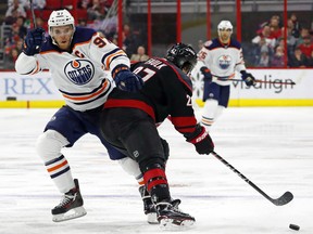 Carolina Hurricanes' Justin Faulk (27) shoves Edmonton Oilers' Connor McDavid (97) off the puck during the second period of an NHL hockey game, Friday, Feb. 15, 2019, in Raleigh, N.C.