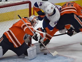 Edmonton Oilers goalie Mikko Koskinen (19) makes a save on New York Islanders Tom Kuhnhackl (14) as he gets checked by Darnell Nurse (25) during NHL action at Rogers Place in Edmonton, February 21, 2019.