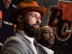 B.C. Lions GM Ed Hervey, back, and quarterback Mike Reilly listen during a news conference after Reilly signed a four-year contract with the team, in Surrey, B.C., on Feb. 12, 2019.