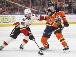 Calgary Flames' Noah Hanifin (55) and Edmonton Oilers' Alex Chiasson (39) battle for the puck during second period NHL action in Edmonton on Saturday, Jan. 19, 2019.