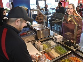 Labour Minister Christina Gray watches worker Shawn Mohammed make her donair after speaking with co-owner Adil Asim of Prime Time Donair & Kabab, to discuss recent changes to Alberta's employment standards in downtown Edmonton, January 23, 2018. Ed Kaiser/Postmedia