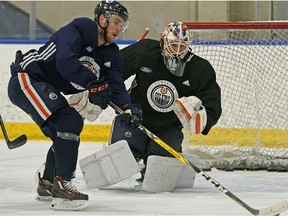 Edmonton Oilers captain Connor McDavid skates past goalie Mikko Koskinen during team practice in Edmonton on Feb. 12, 2019.