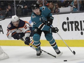 Edmonton Oilers center Connor McDavid, left, reaches for the puck next to San Jose Sharks right wing Joonas Donskoi (27), from Finland, during the second period of an NHL hockey game in San Jose, Calif., Tuesday, Jan. 8, 2019.