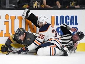 Tomas Nosek #92 of the Vegas Golden Knights and Darnell Nurse #25 of the Edmonton Oilers crash into linesman Derek Nansen as they go after the puck in the second period of their game at T-Mobile Arena on March 17, 2019 in Las Vegas, Nevada.