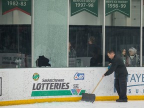 A grounds crew worker at Saskatoon's Merlis Belsher Place shovels broken glass during a break in Game 3 of the Canada West men's hockey final between the University of Alberta Golden Bears and University of Saskatchewan Huskies after a player's foot accidentally went through the pane on Sunday, March 3, 2019.