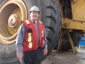 North American Construction's President and COO Joe Lambert is dwarfed by one of the company's 300 monster haul-trucks.GRAHAM HICKS/EDMONTON SUN