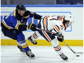 St. Louis Blues' Jay Bouwmeester (19) reaches for the puck with Edmonton Oilers' Connor McDavid (97) during the second period of an NHL hockey game, Wednesday, Dec. 5, 2018, in St. Louis.