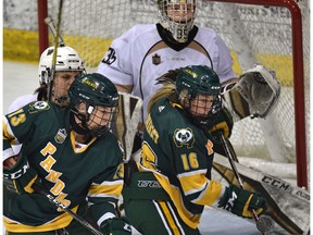 University of Alberta Pandas Alex Poznikoff (16) and Amy Boucher (13) try to deflect the puck on Manitoba Bisons goalie Lauren Taraschuk (35) during the Canada West Final at Clare Drake Arena in Edmonton, March 2, 2019.