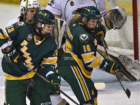 University of Alberta Pandas Alex Poznikoff (16) and Amy Boucher (13) try to deflect the puck on Manitoba Bisons goalie Lauren Taraschuk (35) during the Canada West Final at Clare Drake Arena in Edmonton on Saturday, March 2, 2019.